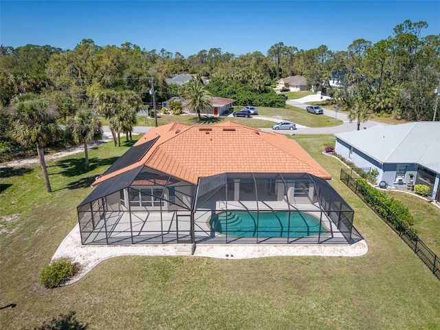 outdoor pool featuring glass enclosure, a lawn, a patio, and fence