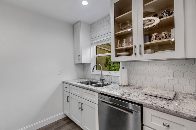 kitchen featuring light stone counters, baseboards, a sink, decorative backsplash, and dishwasher