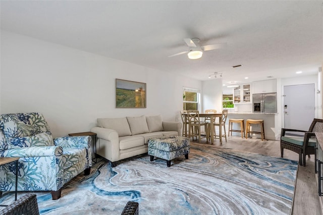 living area with visible vents, ceiling fan, and wood finished floors