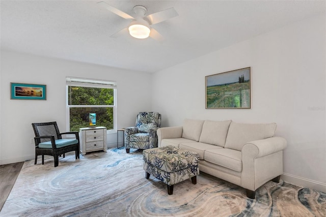 living area featuring wood finished floors, baseboards, and ceiling fan