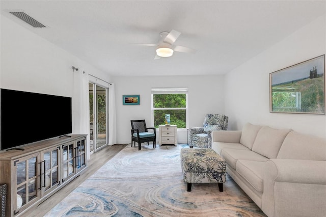 living room with wood finished floors, visible vents, and ceiling fan