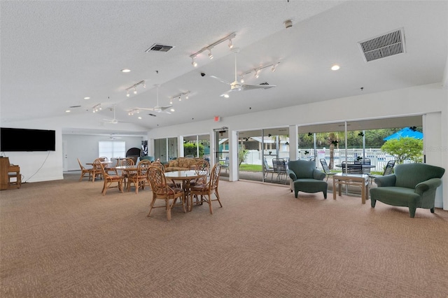 carpeted dining room with lofted ceiling, rail lighting, visible vents, and a textured ceiling