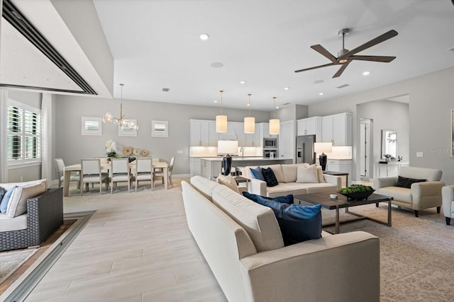 living area with recessed lighting, ceiling fan with notable chandelier, and light wood-type flooring