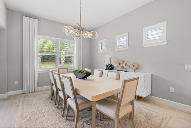 dining area featuring light wood-style flooring, baseboards, and a chandelier