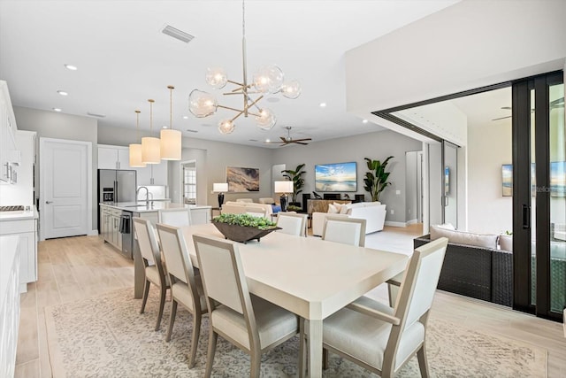 dining space with recessed lighting, ceiling fan with notable chandelier, visible vents, and wood finish floors