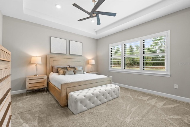 carpeted bedroom with a tray ceiling, recessed lighting, baseboards, and ceiling fan