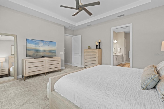 bedroom with a raised ceiling, baseboards, visible vents, and light carpet