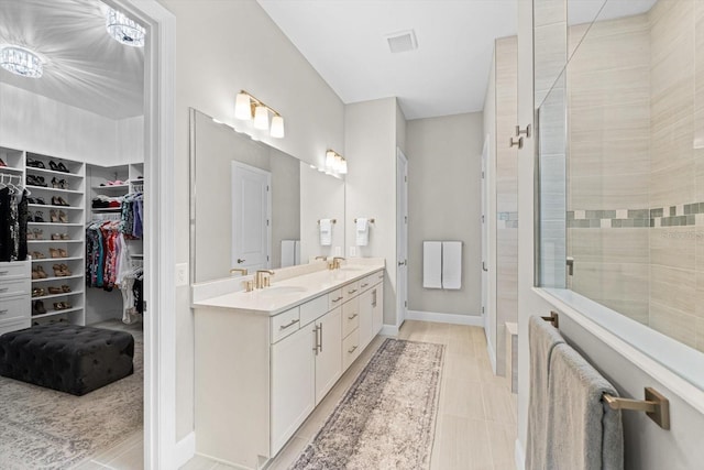 bathroom featuring double vanity, a walk in closet, walk in shower, and a sink