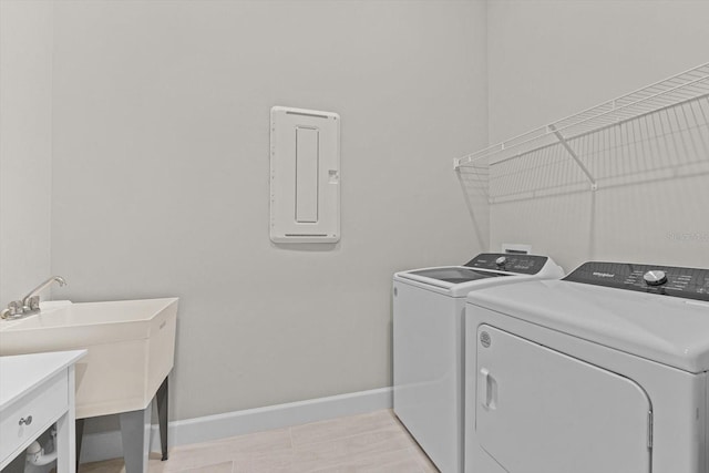 washroom featuring independent washer and dryer, a sink, electric panel, baseboards, and laundry area