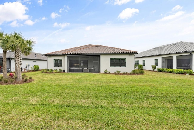 back of house featuring a tile roof, a lawn, a sunroom, and stucco siding