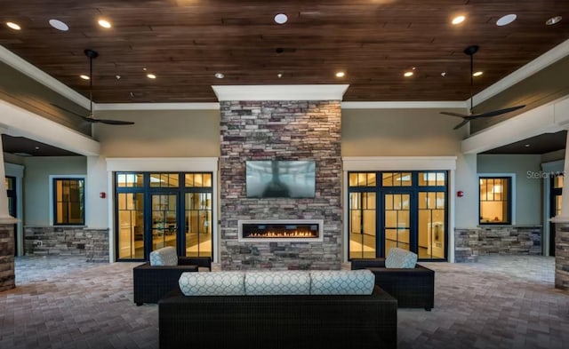 living area featuring a stone fireplace, wooden ceiling, and ornamental molding