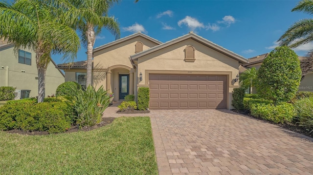 view of front of house with an attached garage, decorative driveway, and stucco siding