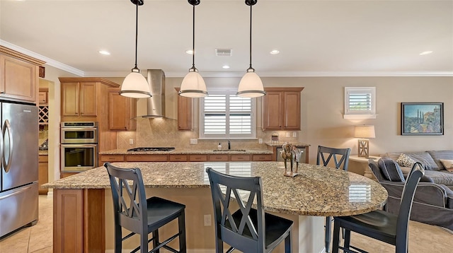 kitchen with stainless steel appliances, visible vents, open floor plan, a sink, and wall chimney range hood