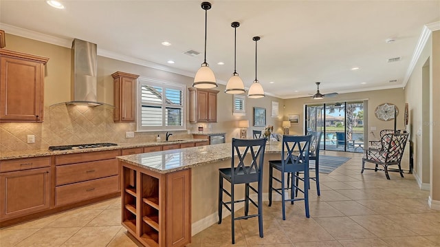 kitchen with stainless steel gas cooktop, wall chimney range hood, plenty of natural light, and a center island