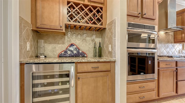 kitchen with light stone counters, beverage cooler, stainless steel appliances, exhaust hood, and tasteful backsplash