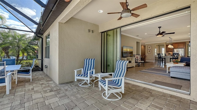 view of patio / terrace featuring a ceiling fan, outdoor dining space, and glass enclosure