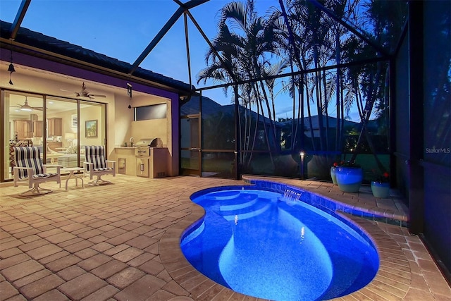 outdoor pool featuring glass enclosure, a patio area, grilling area, and an outdoor kitchen