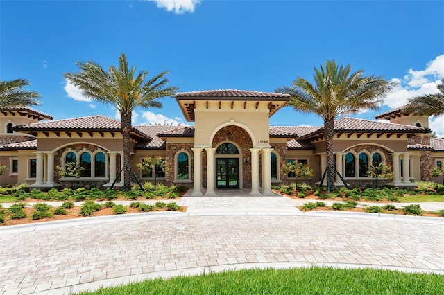 view of front of property featuring stucco siding, a tile roof, stone siding, and french doors