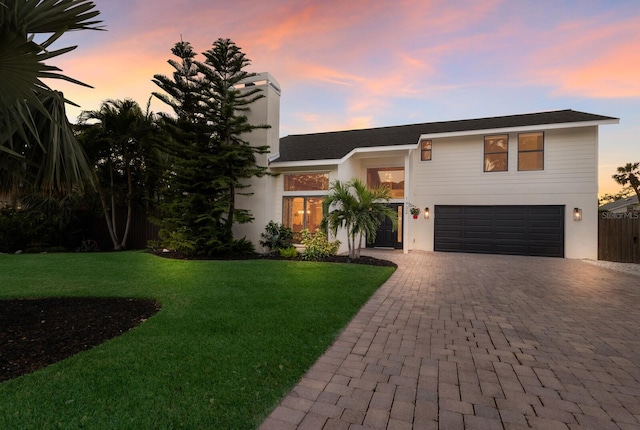 view of front of home featuring decorative driveway, an attached garage, a front yard, and stucco siding