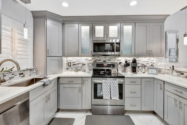 kitchen with appliances with stainless steel finishes, a sink, and gray cabinetry