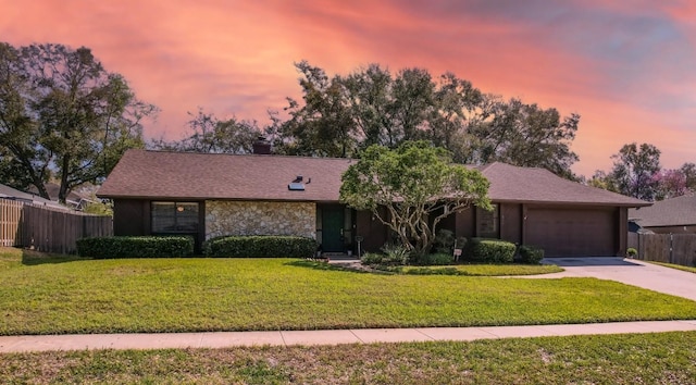 view of front of home with a garage, fence, driveway, stone siding, and a front yard