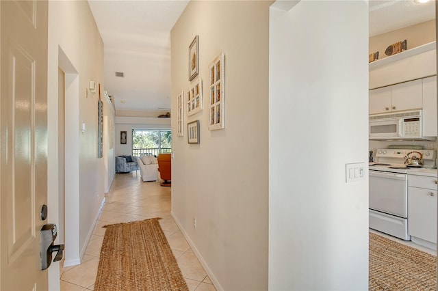 hallway with light tile patterned floors, visible vents, and baseboards