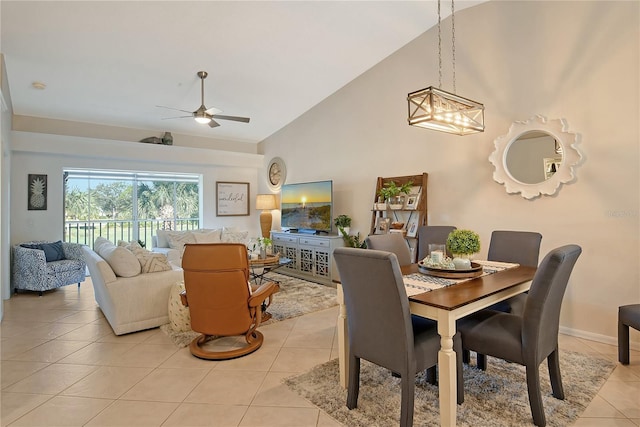 dining area with light tile patterned flooring, ceiling fan with notable chandelier, and high vaulted ceiling