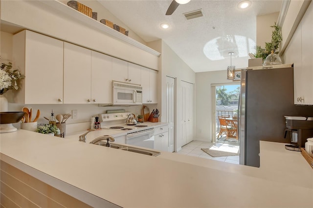 kitchen featuring visible vents, a sink, a textured ceiling, white appliances, and lofted ceiling