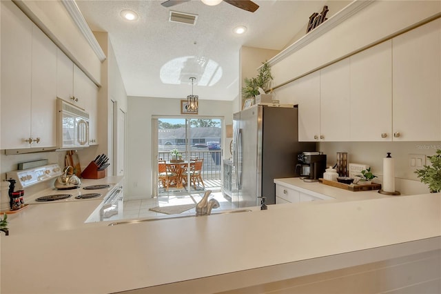 kitchen featuring visible vents, light countertops, hanging light fixtures, white appliances, and a textured ceiling