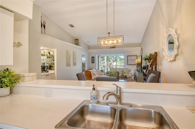 kitchen with visible vents, open floor plan, light countertops, vaulted ceiling, and a sink