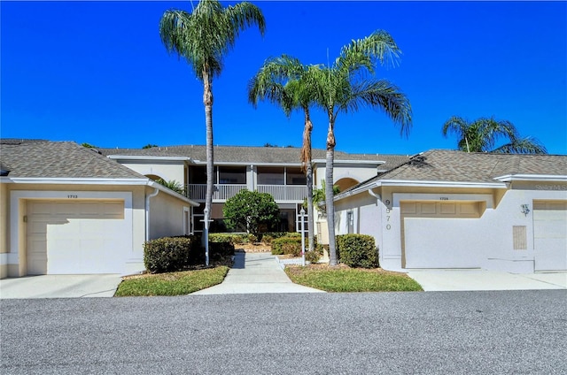 view of front of home with a shingled roof, concrete driveway, a garage, and stucco siding