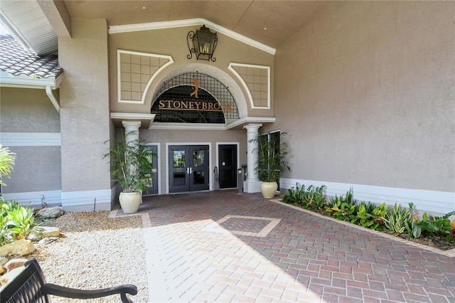 view of exterior entry featuring a tiled roof, french doors, and stucco siding