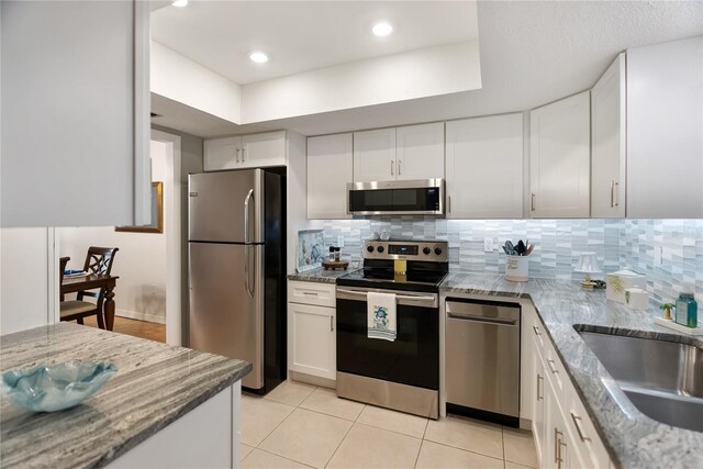 kitchen with stainless steel appliances, white cabinets, a sink, and tasteful backsplash