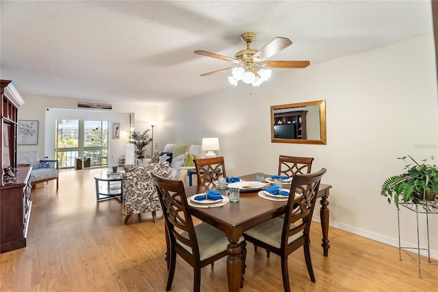 dining space featuring a ceiling fan, light wood-type flooring, a textured ceiling, and baseboards