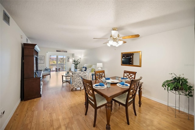 dining space featuring baseboards, visible vents, light wood-style flooring, ceiling fan, and a textured ceiling