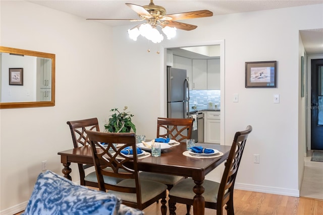 dining room with baseboards, ceiling fan, and light wood finished floors