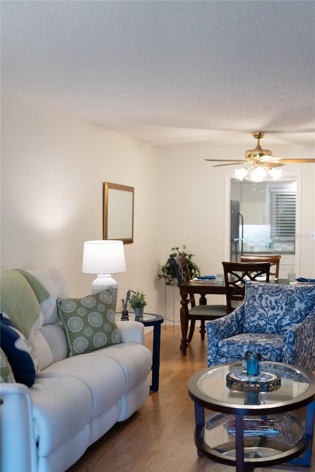 living area with a textured ceiling, wood finished floors, and a ceiling fan