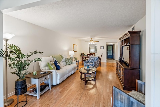 living room featuring light wood-style floors, a ceiling fan, and a textured ceiling