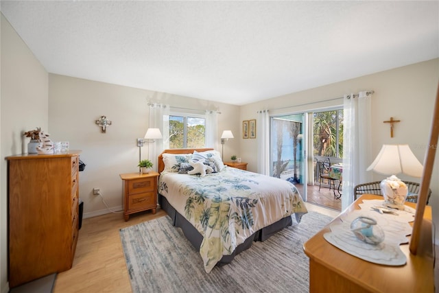 bedroom featuring light wood-type flooring, access to exterior, multiple windows, and baseboards