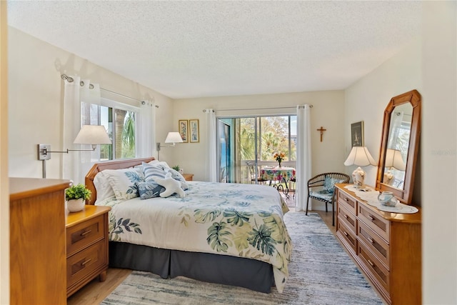 bedroom featuring light wood-type flooring, multiple windows, and a textured ceiling