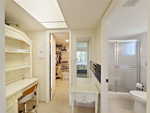 full bathroom featuring a stall shower, visible vents, toilet, tile patterned flooring, and a walk in closet