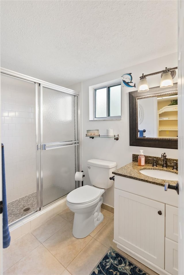 full bathroom featuring toilet, a stall shower, vanity, a textured ceiling, and tile patterned flooring