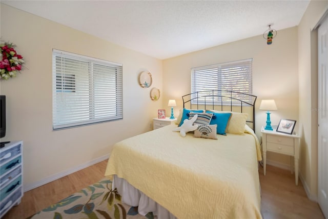 bedroom featuring light wood finished floors and baseboards