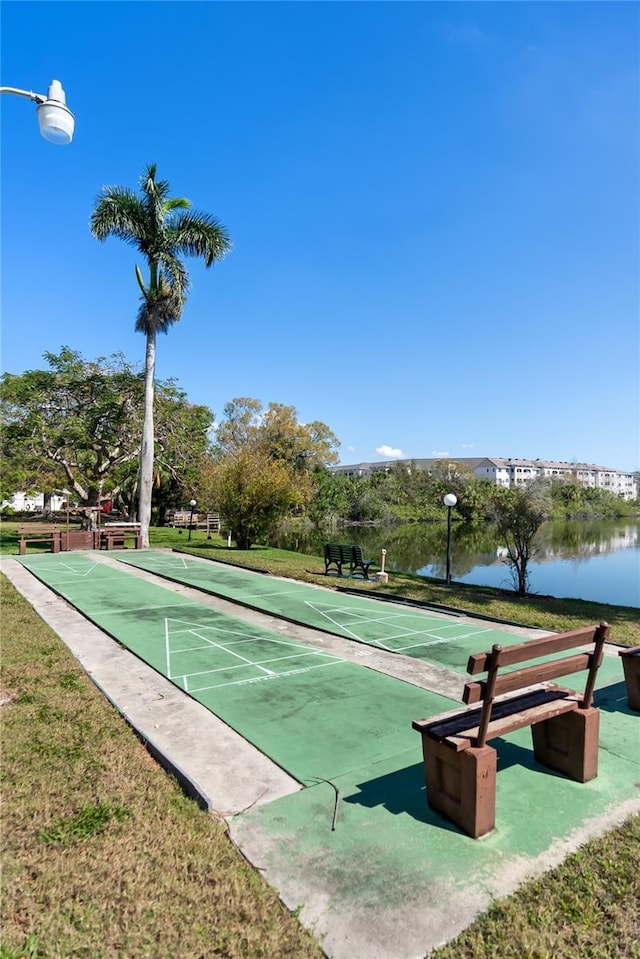 view of community with a water view, shuffleboard, and a lawn