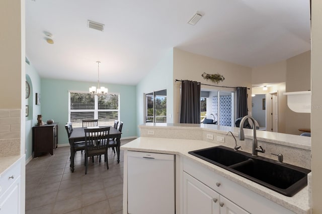 kitchen featuring visible vents, a chandelier, white dishwasher, white cabinetry, and a sink