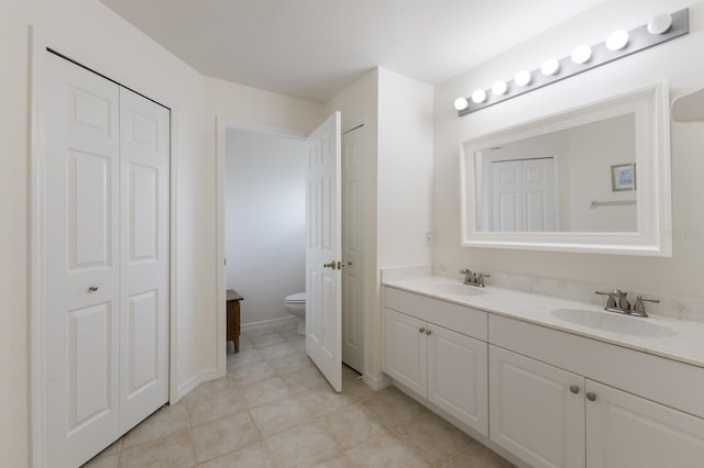 full bath featuring a closet, a sink, toilet, and double vanity