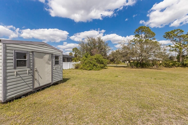 view of yard featuring a storage shed, fence, and an outbuilding