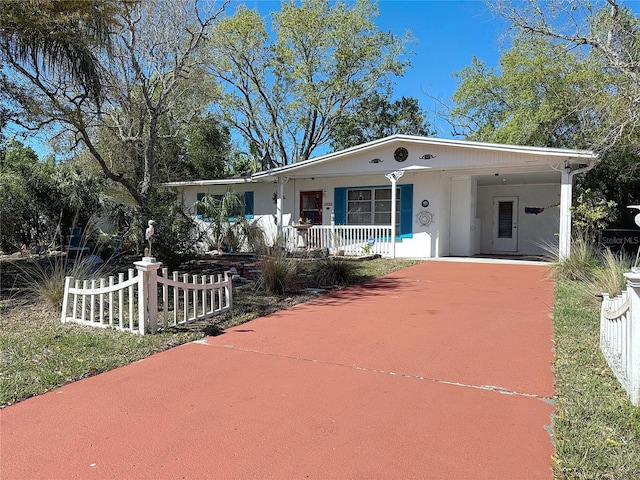 view of front of home featuring concrete driveway, a porch, fence, and an attached carport