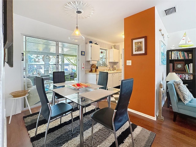 dining space with baseboards, visible vents, and wood finished floors