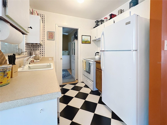 kitchen featuring light countertops, a sink, washer / dryer, white appliances, and tile patterned floors